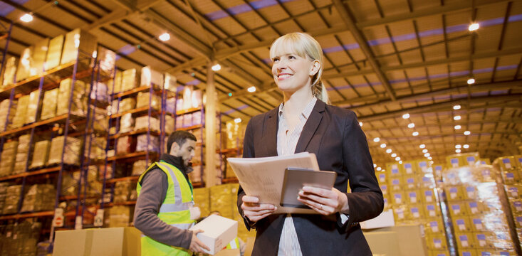 Businesswoman smiling in warehouse - Powered by Adobe