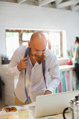 Businessman eating breakfast and using laptop