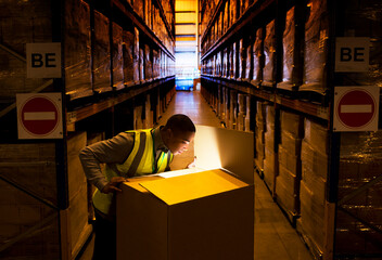 Worker opening glowing box in warehouse - obrazy, fototapety, plakaty