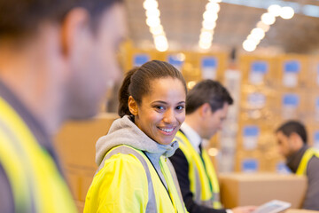 Worker smiling in warehouse - obrazy, fototapety, plakaty