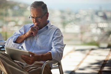 Older man using tablet computer outdoors