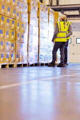 Obraz premium Workers examining stacks of boxes in warehouse