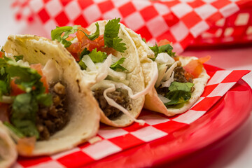 Tacos y tortas de barbacoa sobre mantel de cuadros rojos y fondo blanco
