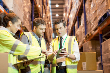 Businessman and workers talking in warehouse - obrazy, fototapety, plakaty