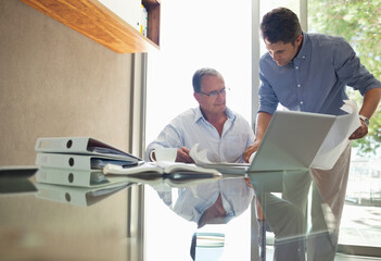 Older and younger man talking at desk