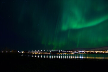 aurora borealis over tromso city island, fjord and snowy mountain