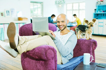 Obraz premium Man using laptop in armchair