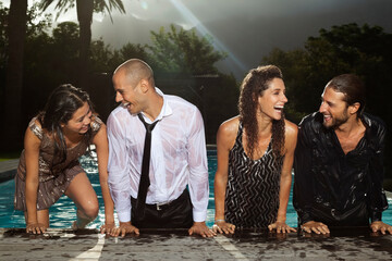 Fully dressed friends climbing out of swimming pool