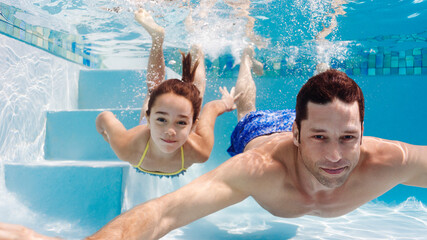 Father and daughter swimming in pool