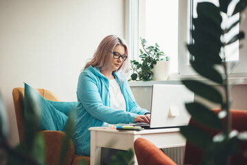 Busy senior caucasian businesswoman working at the laptop remotely wearing eyeglasses and blonde hair