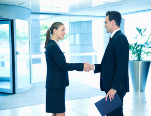 Smiling businessman and businesswoman handshaking in lobby