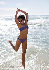 Enthusiastic woman in bikini jumping on beach