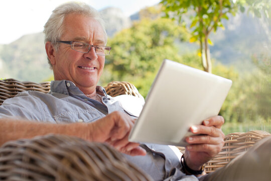 Smiling senior man using digital tablet on patio