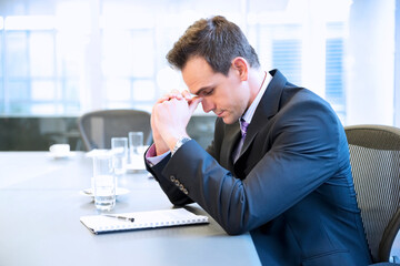 Businessman with head in hands in conference room