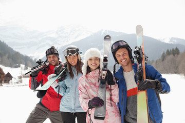 Portrait of smiling friends with skis in snowy field