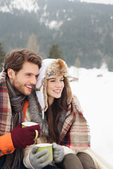 Happy couple drinking coffee in snowy field