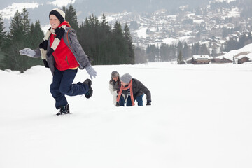 Mother and sons playing in snowy field