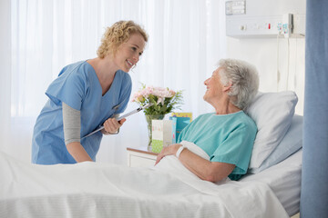 Nurse and aging patient talking in hospital room
