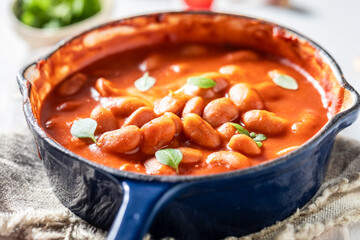 Hot baked beans with garlic on white table