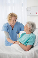 Nurse and senior patient talking in hospital room