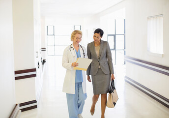 Doctor and businesswoman talking in hospital corridor