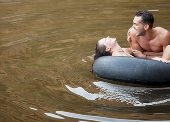Couple playing in inner tube on lake