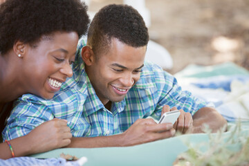 Couple using cell phone on blanket