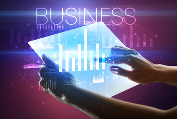 Hand holding futuristic tablet with BUSINESS inscription above, modern business concept