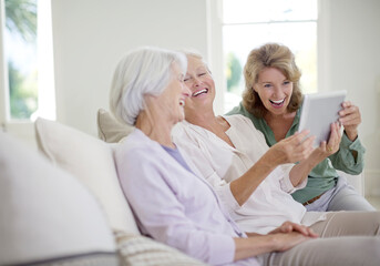 Older women using digital tablet on sofa