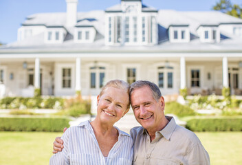 Portrait of smiling senior couple in front of house