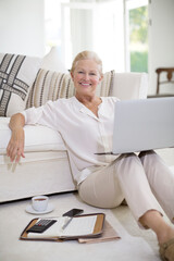 Senior woman using laptop on living room floor