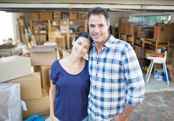 Obraz premium Portrait of smiling couple outside garage among cardboard boxes