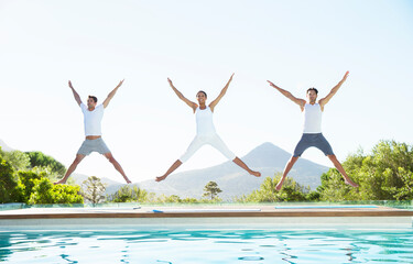 People jumping with arms and legs outstretched at poolside