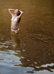 Woman standing with hands in hair in river