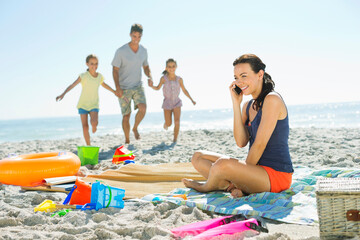 Fototapeta premium Woman talking on cell phone at beach