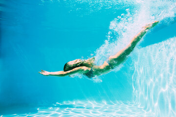Woman diving into swimming pool - obrazy, fototapety, plakaty