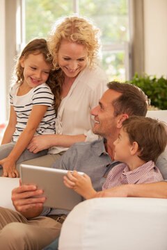 Family Using Digital Tablet On Sofa