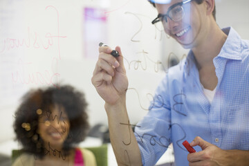 Business people writing on glass in office