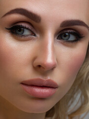 Close-up portrait of the cleanliness face of a beautiful woman with dark black smoky eyes makeup, natural full lips. Sexy model with clean shiny skin, clean face, long curly hair. glamorous image