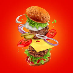 The hamburger with flying ingredients on red background