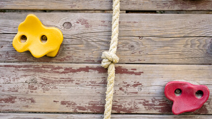 Colorful plastic grips and ropes on wall at cliff climbing center