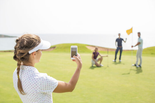Woman photographing friends on golf course