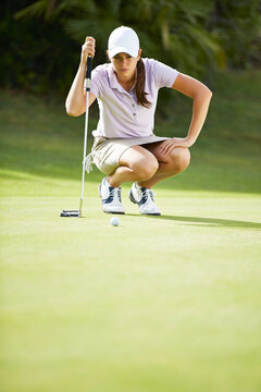 Woman Preparing To Putt On Golf Course