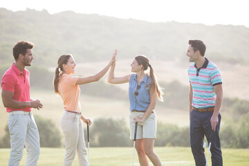 Friends high fiving on golf course