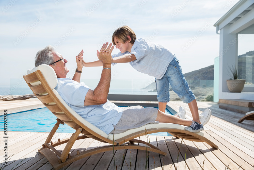 Wall mural Grandfather and grandson playing at poolside