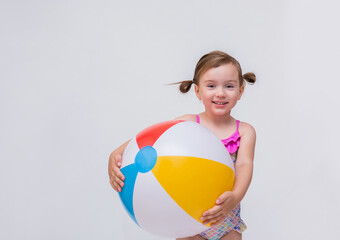 Funny girl with ponytails in a swimsuit and an inflatable ball on a white isolated background with space for text.