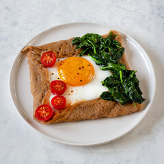 Galette bretonne with fried eggs and spinach.