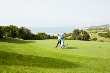 Men walking on golf course overlooking ocean