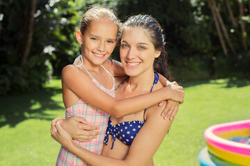 Mother and daughter hugging in backyard