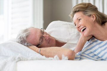 Older couple relaxing on bed - obrazy, fototapety, plakaty